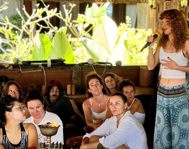 Aliette au micro, transmettant devant un groupe assis en cercle.