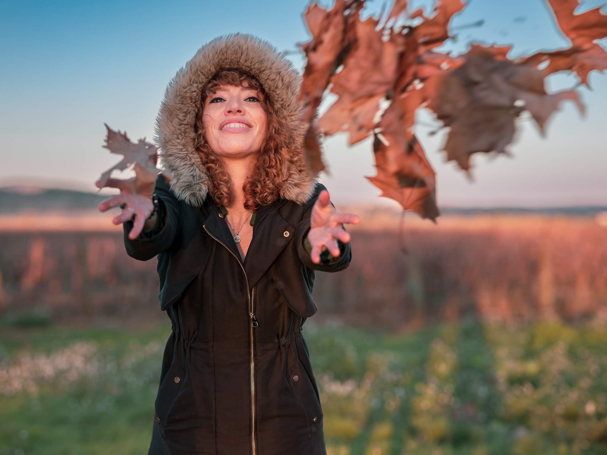 Aliette L'Alouette dans la nature au soleil couchant, capuche de fourrure, lançant des feuilles d'automne.